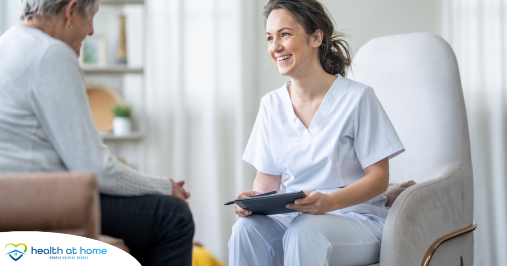 A woman smiles and enjoys her caregiving job as she writes notes down with a client.