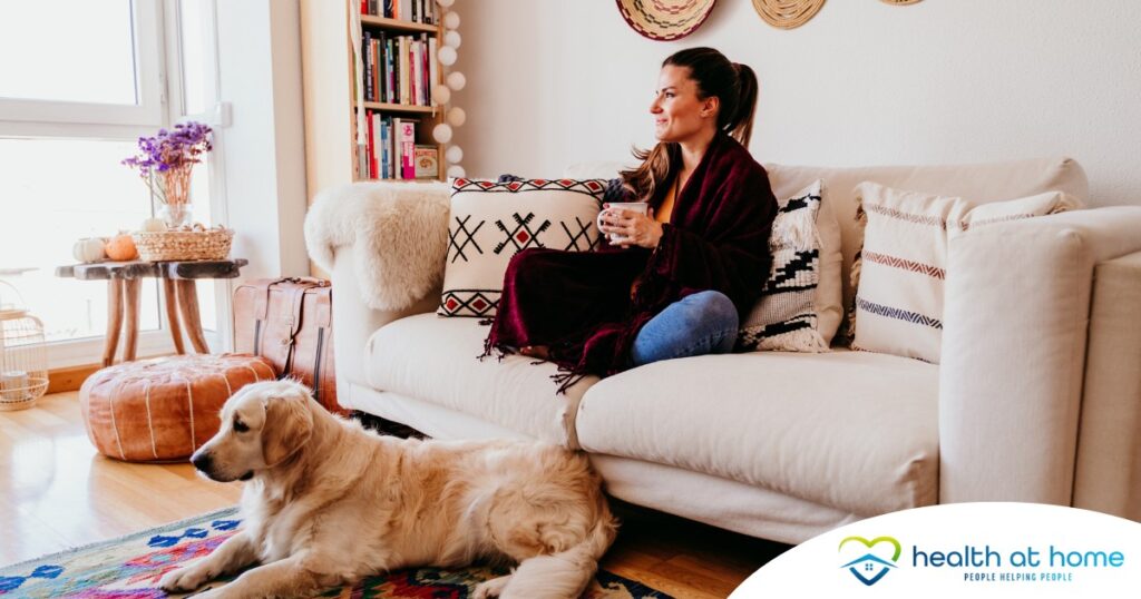 A woman relaxes with her dog while sipping on tea, representing how self-care can combat caregiver stress.