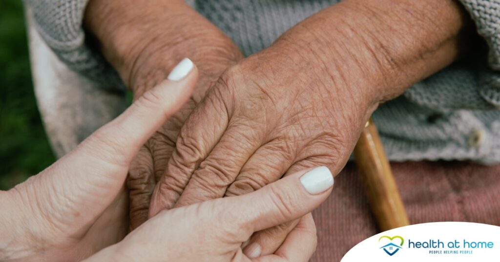 A caregiver holding an older adult's hands represents the support that hospice care can bring.