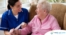 A caregiver demonstrates wound care by wrapping a senior client’s wound.