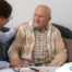 A caregiver compassionately listens to an older man, representing the kind of patience and empathy that help with communicating with clients who have dementia.