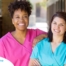 2 smiling women in scrubs represent RN supervisors and the good environment that can be promoted when they work together with caregivers for quality client care.