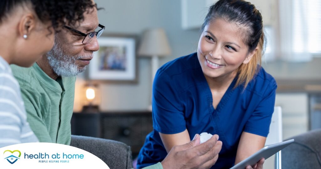 A nurse smiles as she helps an older couple with their medication in the comfort of their own home, showing the benefits of in-home nursing services.