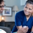 A nurse smiles as she helps an older couple with their medication in the comfort of their own home, showing the benefits of in-home nursing services.