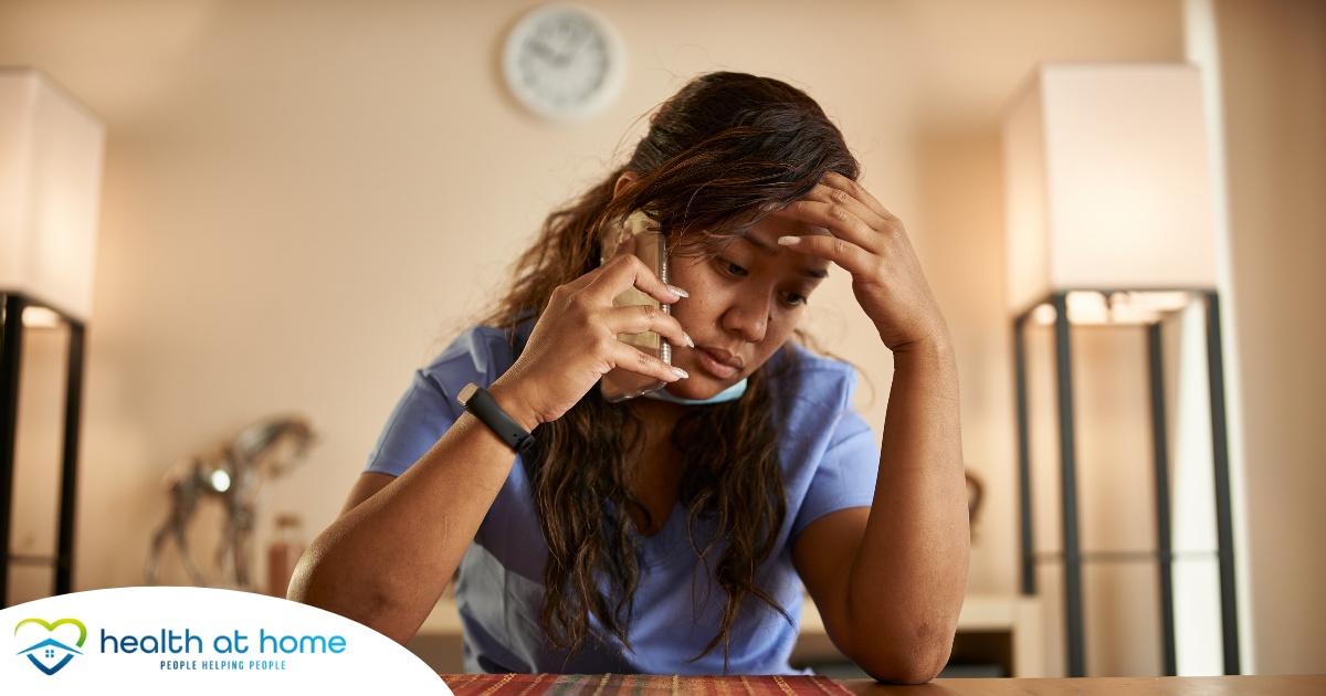 A nurse makes a call while looking extremely exhausted representing the bad effects of nurse burnout.