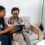 A caregiver talks with a patient while showing her information on a tablet representing the type of thorough communication needed for effective and professional care of home health care patients.