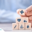 A stack of block with different health related icons represents health insurance which can help with home health care.