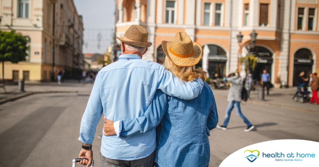 2 older adults hug while on vacation representing the successful outing that can still happen while caring for elderly loved ones.