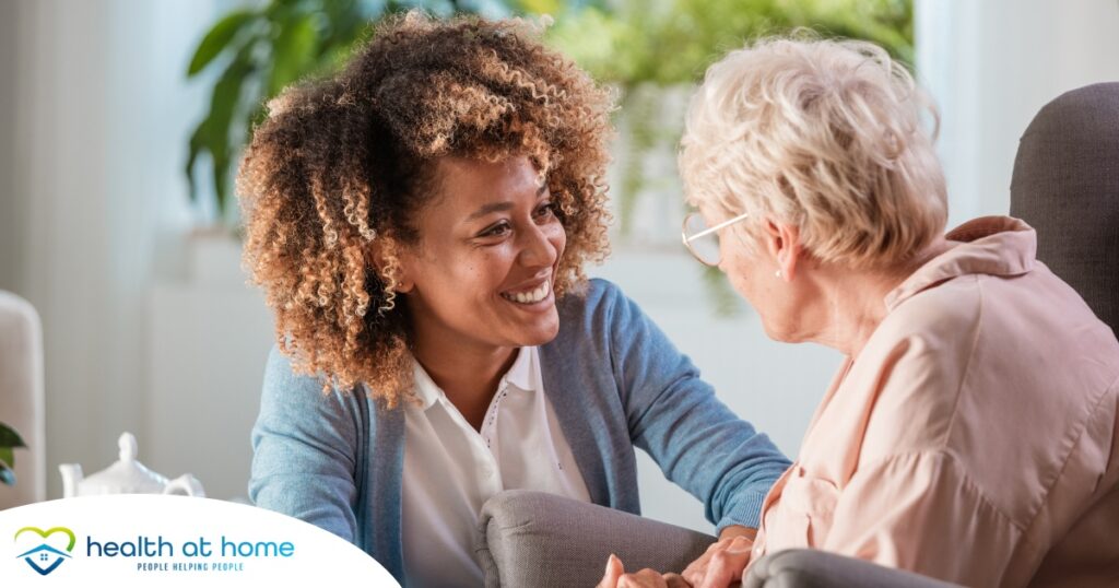 A caregiver warmly speaks with an older client, representing the quality communication that can come with bilingual care.