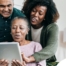 A daughter looks at a tablet with her older parents, representing technology and how ti can help with aging in place