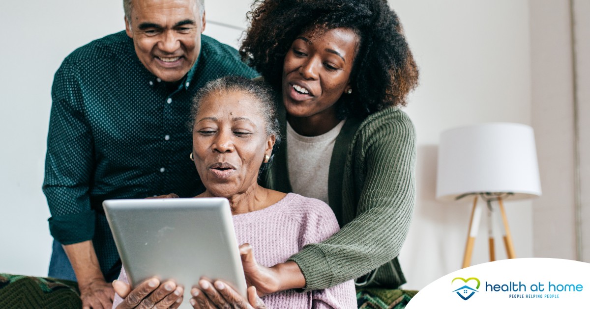 A daughter looks at a tablet with her older parents, representing technology and how ti can help with aging in place