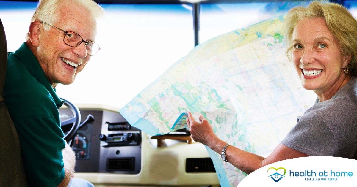 An older couple looks back smiling from the front of an RV, representing how day trips for seniors can help boost the mood of everyone.
