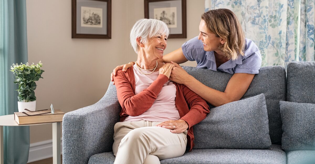 caregiver daughter and elderly mother on couch discussing private duty care