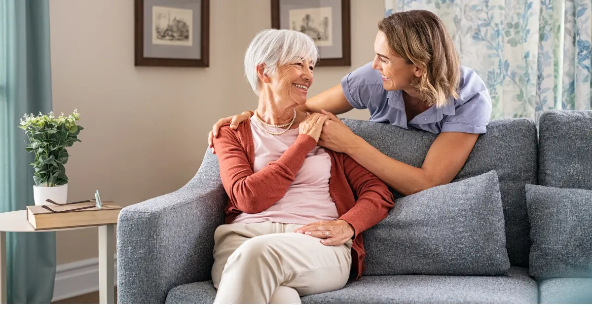 caregiver daughter and elderly mother on couch discussing private duty care
