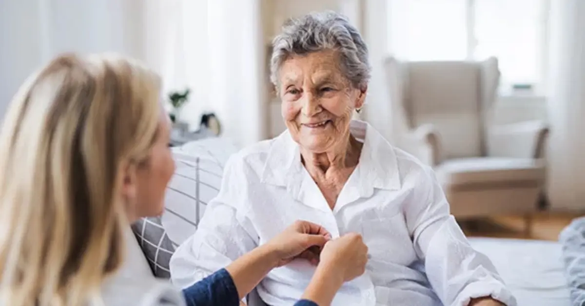dementia at home care provider helping button client's shirt