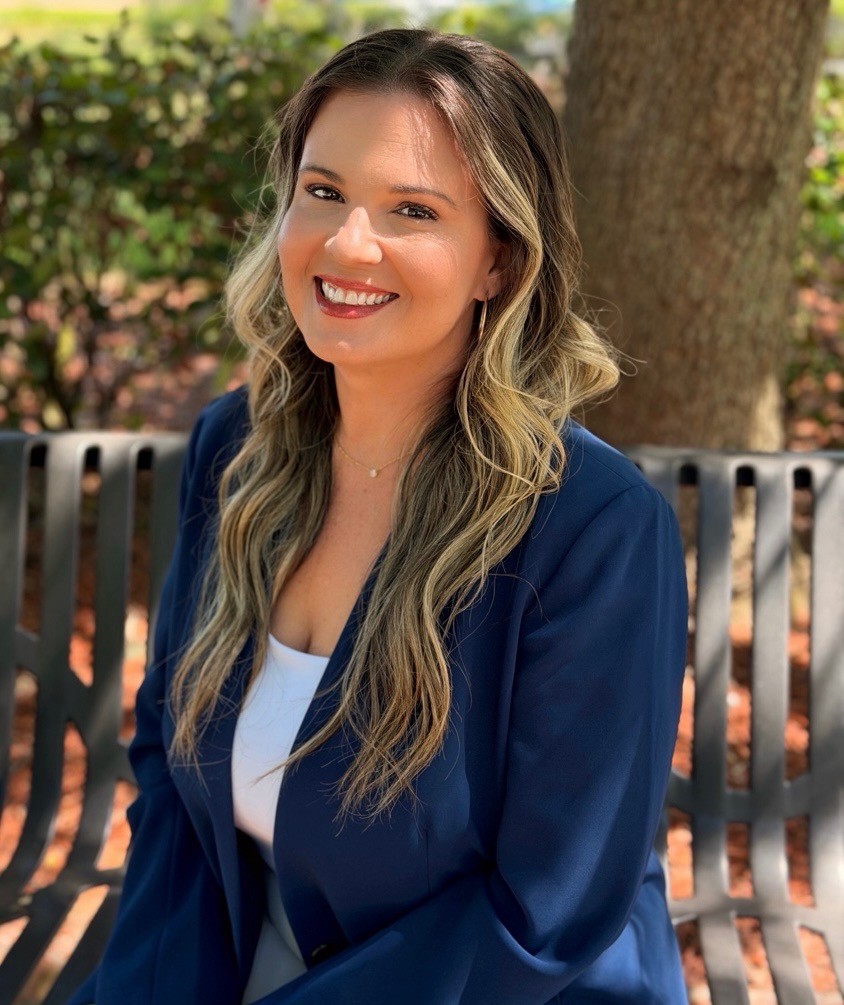 Professional woman in a blue blazer smiles outdoors