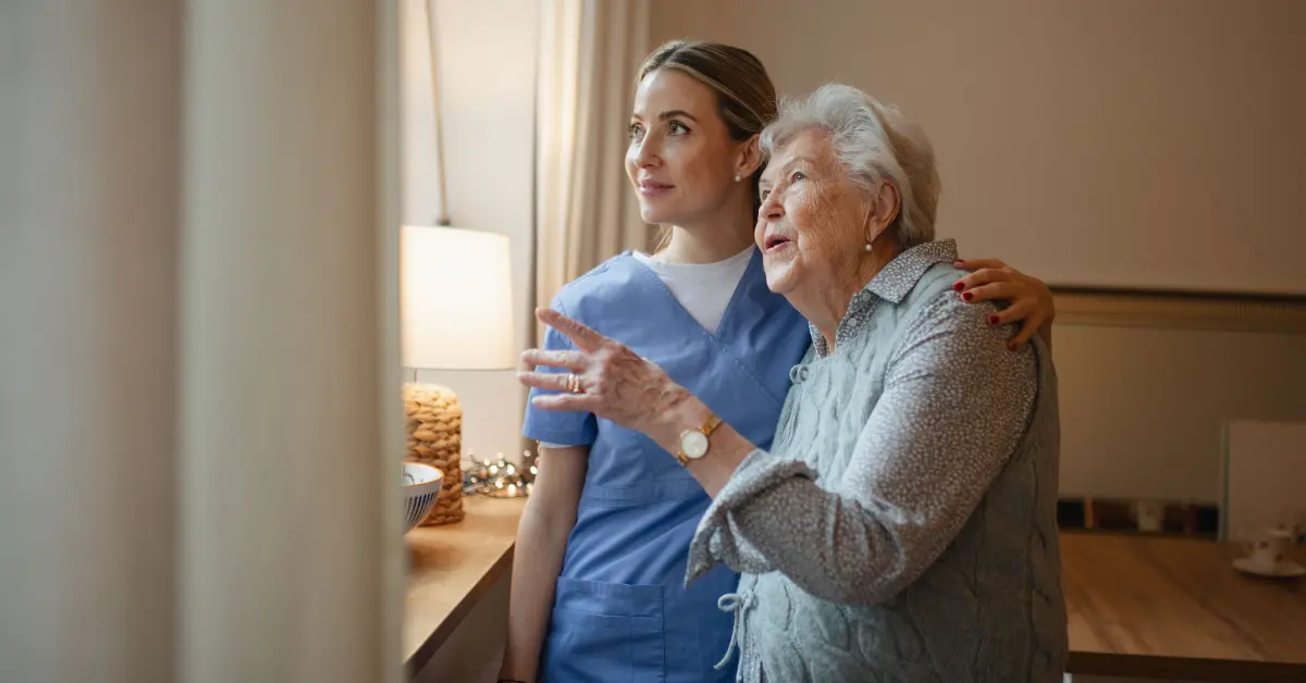 Young caregiver and elderly woman looking out window in Florida companion care