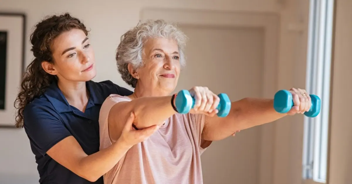 Home care aide in Florida assists senior woman with dumbbell exercises for stroke recovery