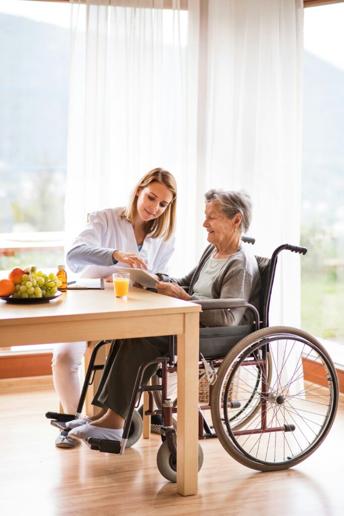 Caregiver assisting senior woman in wheelchair with tablet in Indian River Shores home care setting.